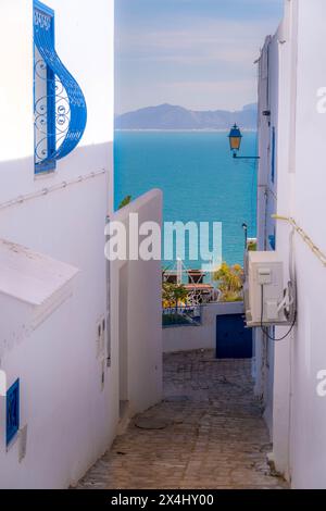 The Mediterranean sea and the Boukornine mountains are seen between the beautiful white-blue buildings in touristic area of Sidi Bou Said in Tunisia. Stock Photo