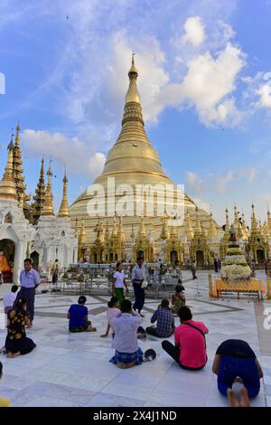 Shwedagon Pagoda, Yangon, Myanmar, Asia, People praying sitting in front of the magnificent Shwedagon Pagoda under a blue sky Stock Photo