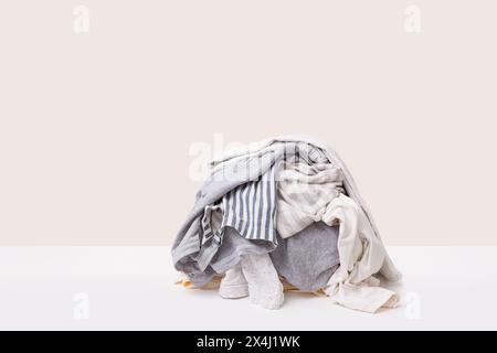 Stack of gray dirty clothes waiting for laundry isolated on light beige background Stock Photo