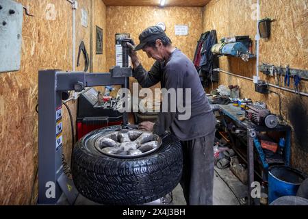 Workshop, man repairing a hole in a car tyre, Kyrgyzstan Stock Photo