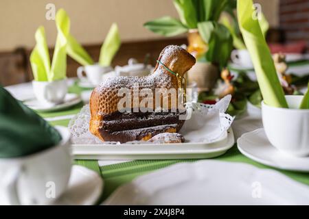 Easter cake shaped like a lamb, dusted with powdered sugar, on a festive table setting Stock Photo