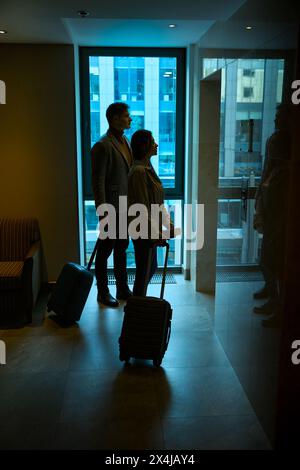 Tourist couple standing in hallway in front of elevator doors Stock Photo