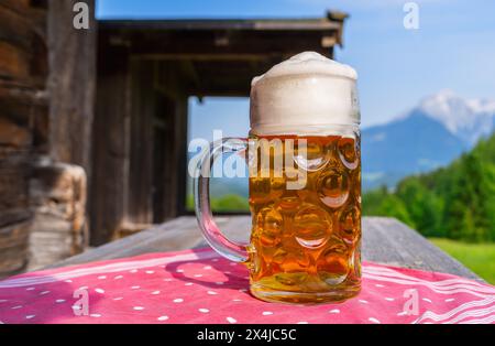 German Beer in a mug on a old wooden table with tablecloth at the bavarian alpine mountains on a alpine hut. Oktoberfest concept image Stock Photo