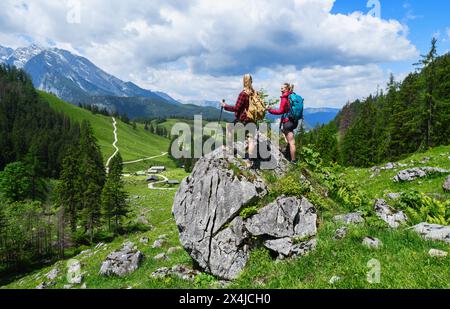 Two female hikers with backpacks standing on a rock and looking in to the valley at the mountains in bavarian alps Stock Photo