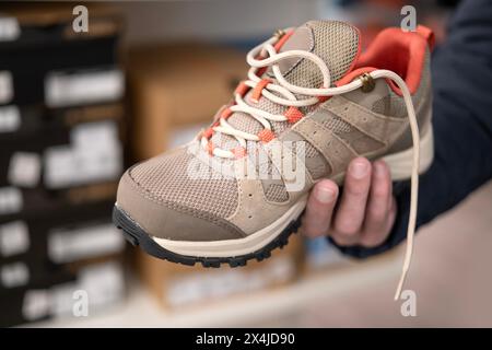 Sturdy brown hiking sneakers with laces in male hands, buying new shoes, modern innovative Sportswear, clothing, footwear, natural suede for outdoor w Stock Photo