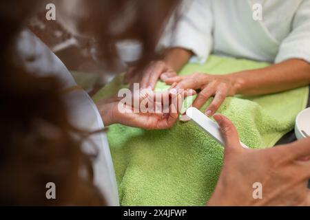 Manicurist buffing nails during a manicure session in a beauty salon Stock Photo