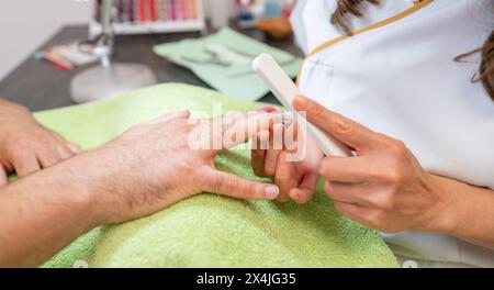 Close-up of hands during a manicure, with a manicurist using a buffer on a client's nails. body care spa treatment concept image Stock Photo