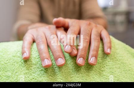 Close-up of well-manicured hands from a man resting on a green towel. body care spa treatment concept image Stock Photo
