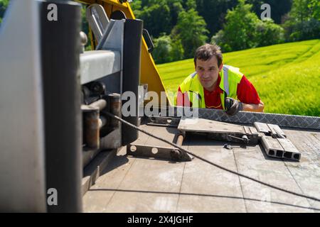 Tow truck driver uses a winch on a tow truck to tow a car Stock Photo