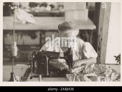 A Puerto-Rican aged woman operating a sewing machine, In the Everglades needlework factory, San Juan, Puerto Rico.  January 1942. Vintage Historic Photography  From the US Government Security Administration Collection 1940s.  Photo Credit: Jack Delano. Stock Photo