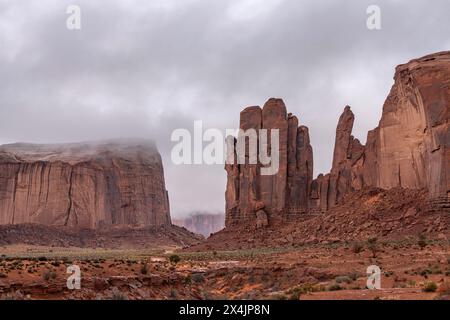 Many areas within Monument Valley host smaller mountainous formations. Shown here is a formation during a rainy day with low clouds lining rocky struc Stock Photo