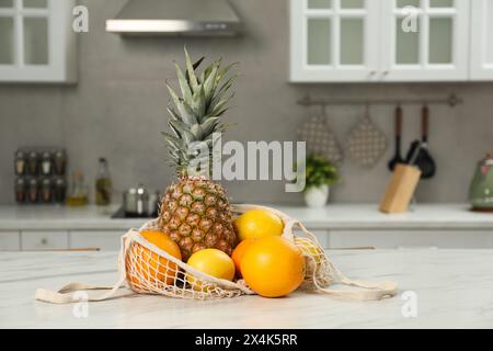 String bag with fresh fruits on light table in kitchen Stock Photo