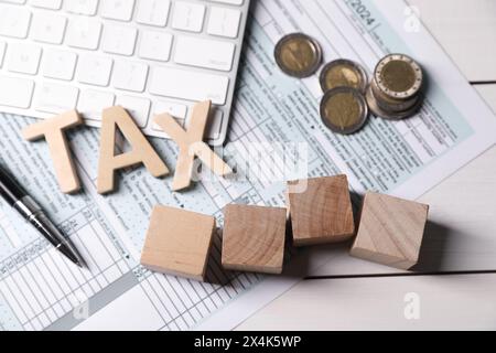 Tax accounting. Cubes with numbers 2024, document, keyboard, coins and pen on white wooden table, flat lay Stock Photo