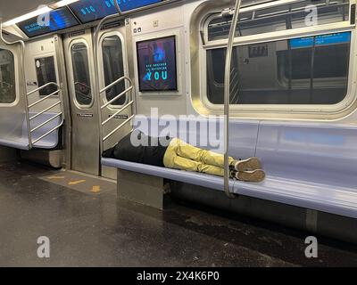 Man sprawled out sleeping on a New York City subway train in the early morning. Stock Photo
