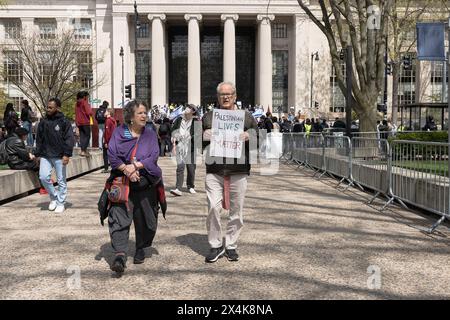 An elderly protester walks toward the MIT encampment holding a placard that reads, 'Palestinian Lives Matter' during the rally. Hundreds attended a pro-Israel rally organized by the New England chapter of the Israeli American Council on the steps of MIT's entrance on Massachusetts Avenue. The rally was one of the largest counter protest held near a Boston-area college encampment protest. The rally was about 30 to 40 yards from the pro-Palestine encampment on the MIT's, campus. Police presence was high in the area and metal barricades were placed to keep the two sides from any clashes. A few Is Stock Photo