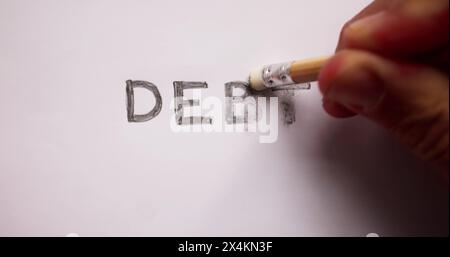 Close-up Of Pencil Eraser Erasing Debt Word On White Paper Stock Photo