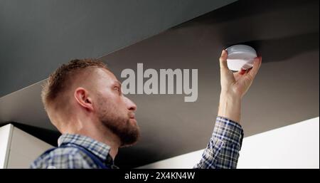 Installing Smoke Detector On Ceiling At Home Stock Photo