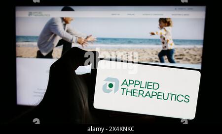 Person holding smartphone with logo of US biopharmaceutical company Applied Therapeutics Inc. in front of website. Focus on phone display. Stock Photo