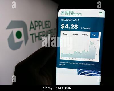Person holding smartphone with webpage of US biopharmaceutical company Applied Therapeutics Inc. with logo. Focus on center of phone display. Stock Photo