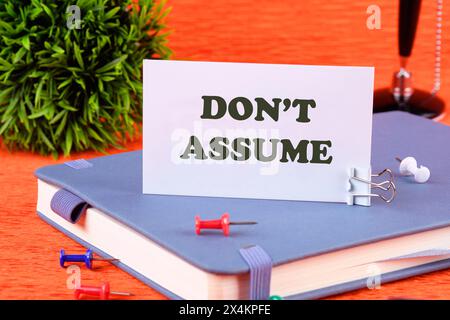 don't assume concept, Don't assume - words on a business card standing on a business notebook Stock Photo