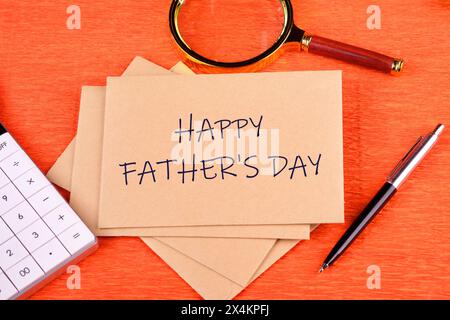 Text HAPPY FATHER'S DAY on postal envelopes in a composition with a calculator, magnifying glass and pen on an orange background Stock Photo