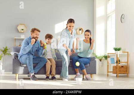 Young family with kids having fun together at home on weekend playing and throwing tennis balls Stock Photo