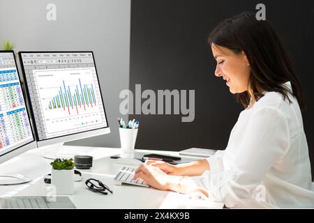 Two women analyzing data on computer desktop spreadsheet Stock Photo