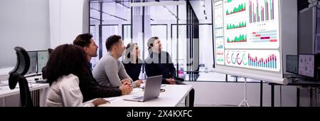 Business group meeting analyzing financial KPIs on computer dashboard Stock Photo