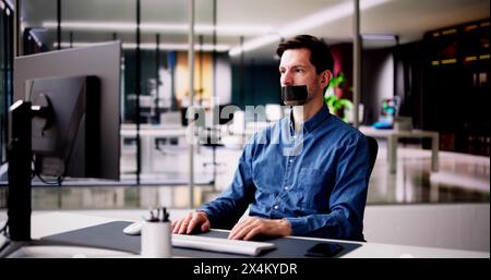 Young Man With Black Duct Tape Over His Mouth In Office Stock Photo