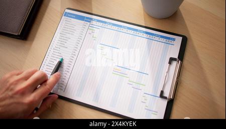Close-up Of Businessman With Pen Working On Gantt Chart At Desk Stock Photo