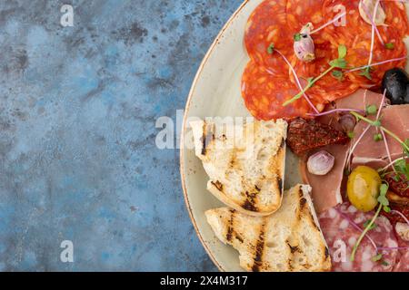catering box with salami, prosciutto and breadsticks, cold cuts, sliced meat and salt with croutons and bread sticks n the plate. Copy space Stock Photo