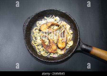 Ilish bhaji for Panta ilish, Bengali new year festive dish. Fried Hilsha slices with chilli and onion. Ilsha fry on black pan. Hilsa fry is popular in Stock Photo