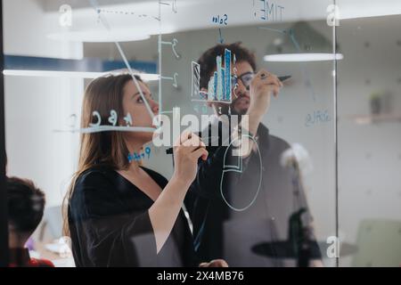 Business professionals brainstorming using sticky notes on a glass wall Stock Photo