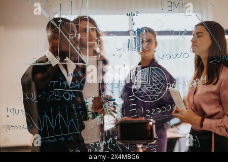 Business team brainstorming and strategizing with sticky notes on glass wall Stock Photo