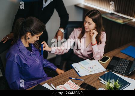 Business colleagues collaboratively analyzing project data in a modern office setting Stock Photo