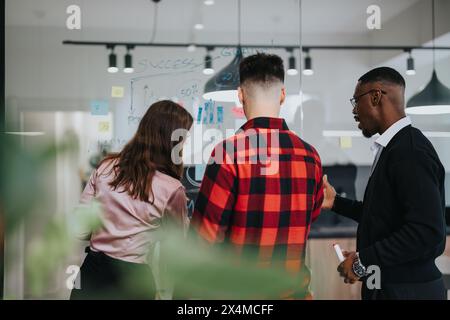 Multiracial team collaborates on creative project in modern office with glass walls and sticky notes Stock Photo