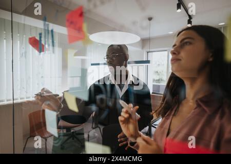 Multiracial team collaboratively brainstorming with sticky notes in a modern office Stock Photo