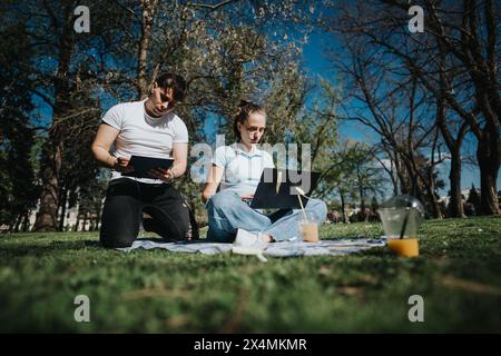 High school students collaborating on a project outdoors on a sunny day Stock Photo