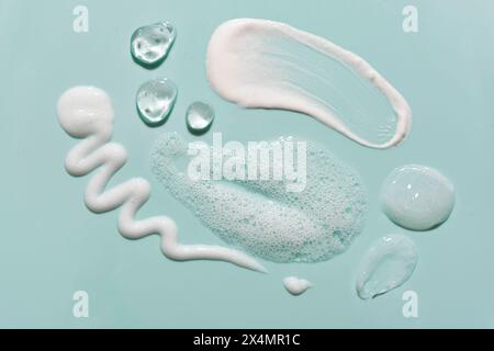Various cosmetic skin care products smear swatches on green blue background close up. Makeup removal products samples - washing gel, foam mousse and m Stock Photo