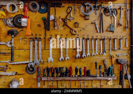 The tools of a workshop hanging on a wooden panel Stock Photo