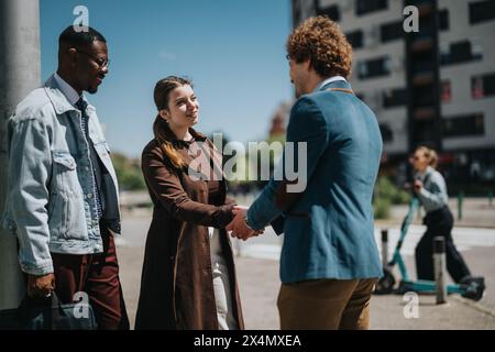 Three diverse professionals greeting each other at an outdoor business meeting in the city Stock Photo