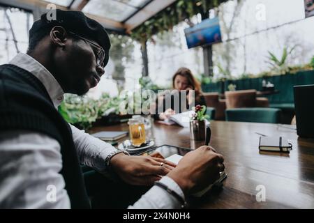 Focused young business people working on projects in a contemporary urban cafe, exemplifying teamwork and entrepreneurship. Stock Photo