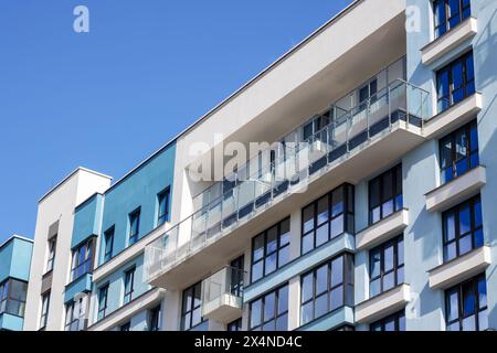 A modern urban design building with a striking facade featuring numerous windows and balconies, offering stunning views of the blue sky. It may be a c Stock Photo