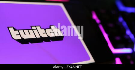Viersen, Germany - May 1. 2024: Smartphone with logo lettering of Twitch live streaming service on computer keyboard Stock Photo