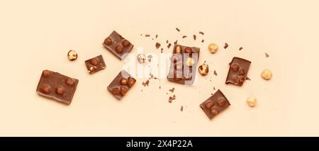 Sweet tasty chocolate pieces with hazelnuts on  beige background Stock Photo