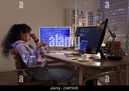 Tired female African-American programmer with eyeglasses sitting in office at night Stock Photo