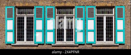 Traditional flemish wooden window shutters in turquoise colors, Gistel, Bruges region, West Flanders, Belgium. Stock Photo