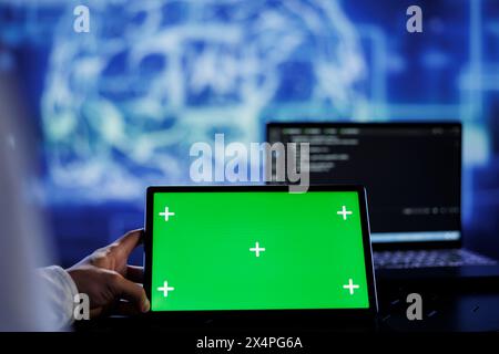 Admin writes code on green screen tablet to visualize artificial intelligence neural networks using augmented reality. High tech workspace supervisor runs AI script on chrome key device Stock Photo