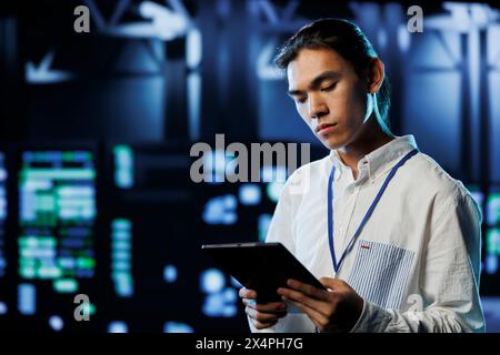 Adept programmer between server hub clusters providing processing resources for businesses worldwide. Overseeing manager fixes data center mainframes tasked with managing massive databases Stock Photo