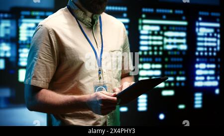 Experienced engineer inspecting operational server racks in computer network security data center. Supercomputers providing processing and memory resources for different workloads Stock Photo